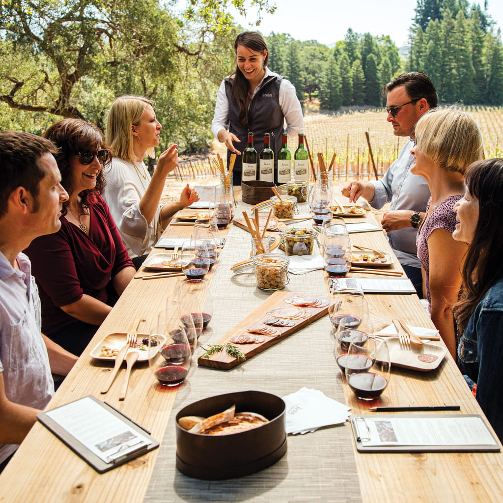 Guests sitting at the picnic table sipping cabernets and eating salumi