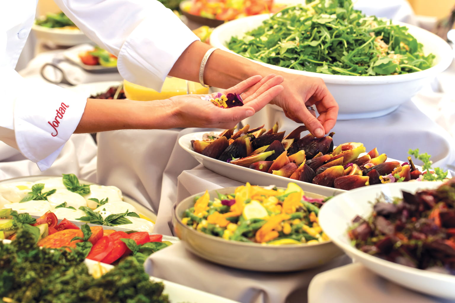 Garnishing a dish with edible flowers on the Harvest Lunch buffet table