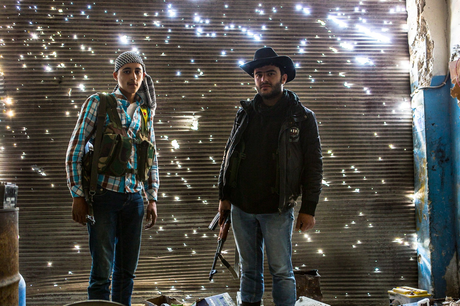 April 20, 2013, Sheikh Maqsood, Aleppo.
Two Kurdish fighters stand in a damaged garage on the front line with Syrian Government forces.